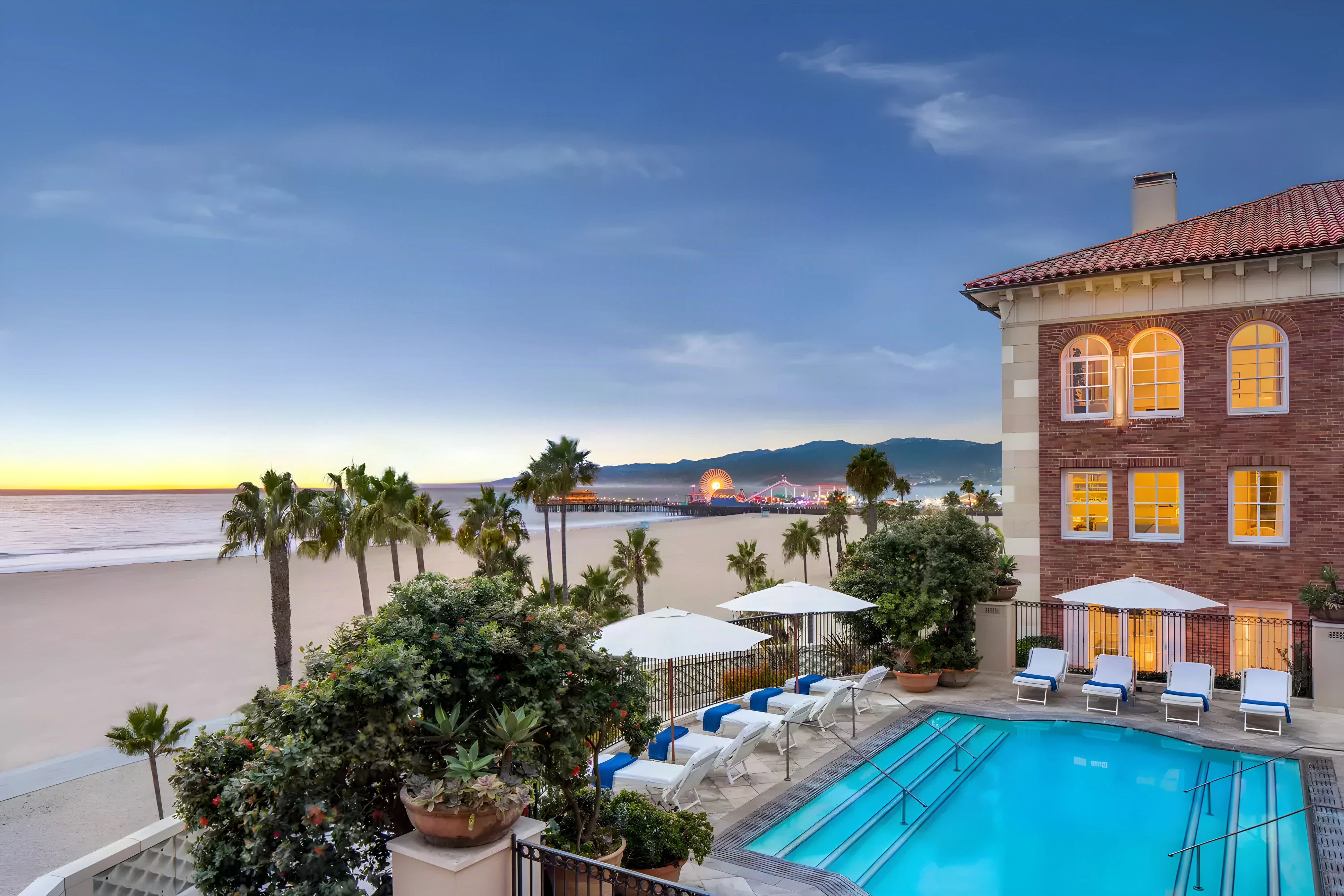 Casa del Mar pool terrace with white loungers and palms above the beach at dusk