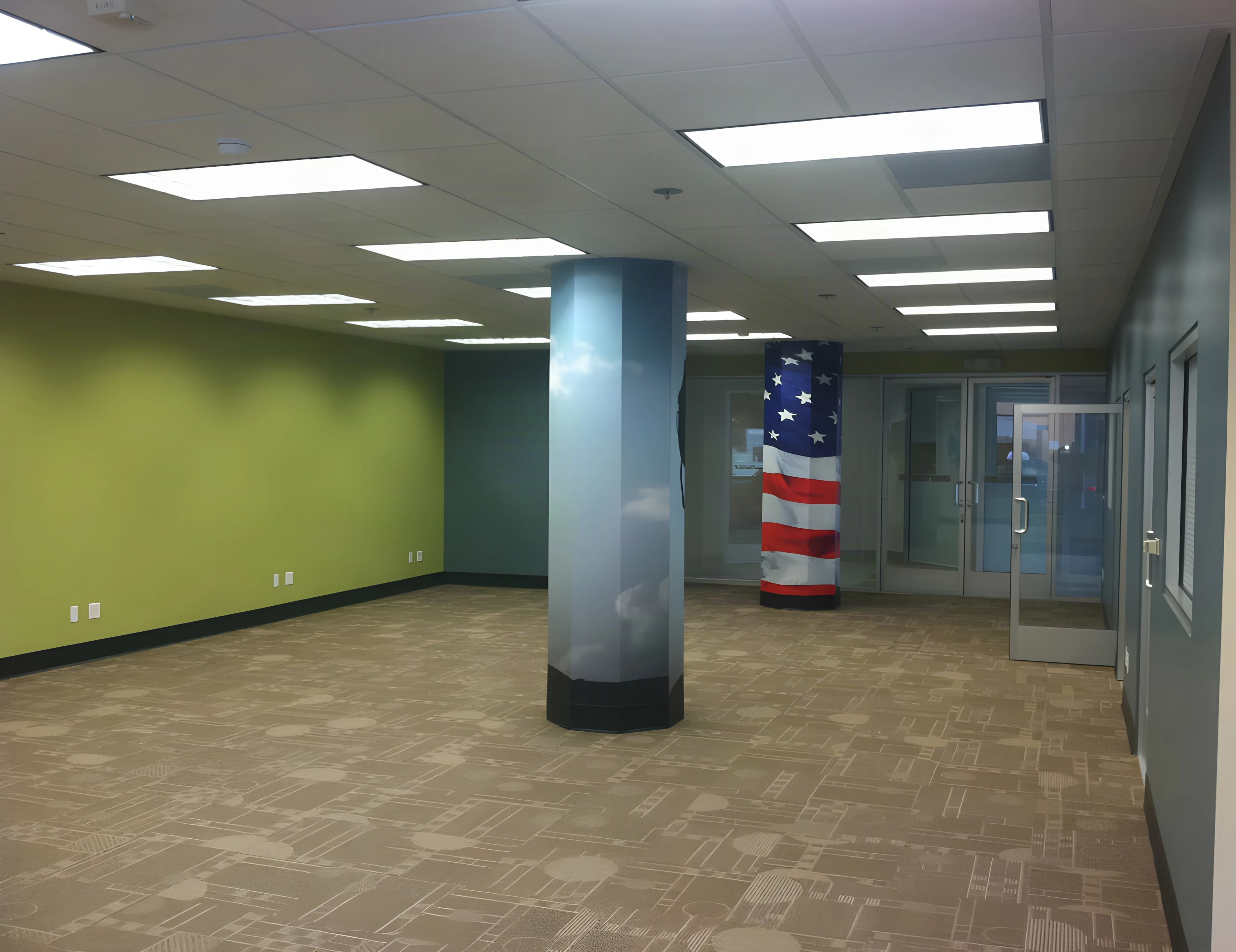 Open office floor with a flag-wrapped column and green feature wall at the Armed Forces center