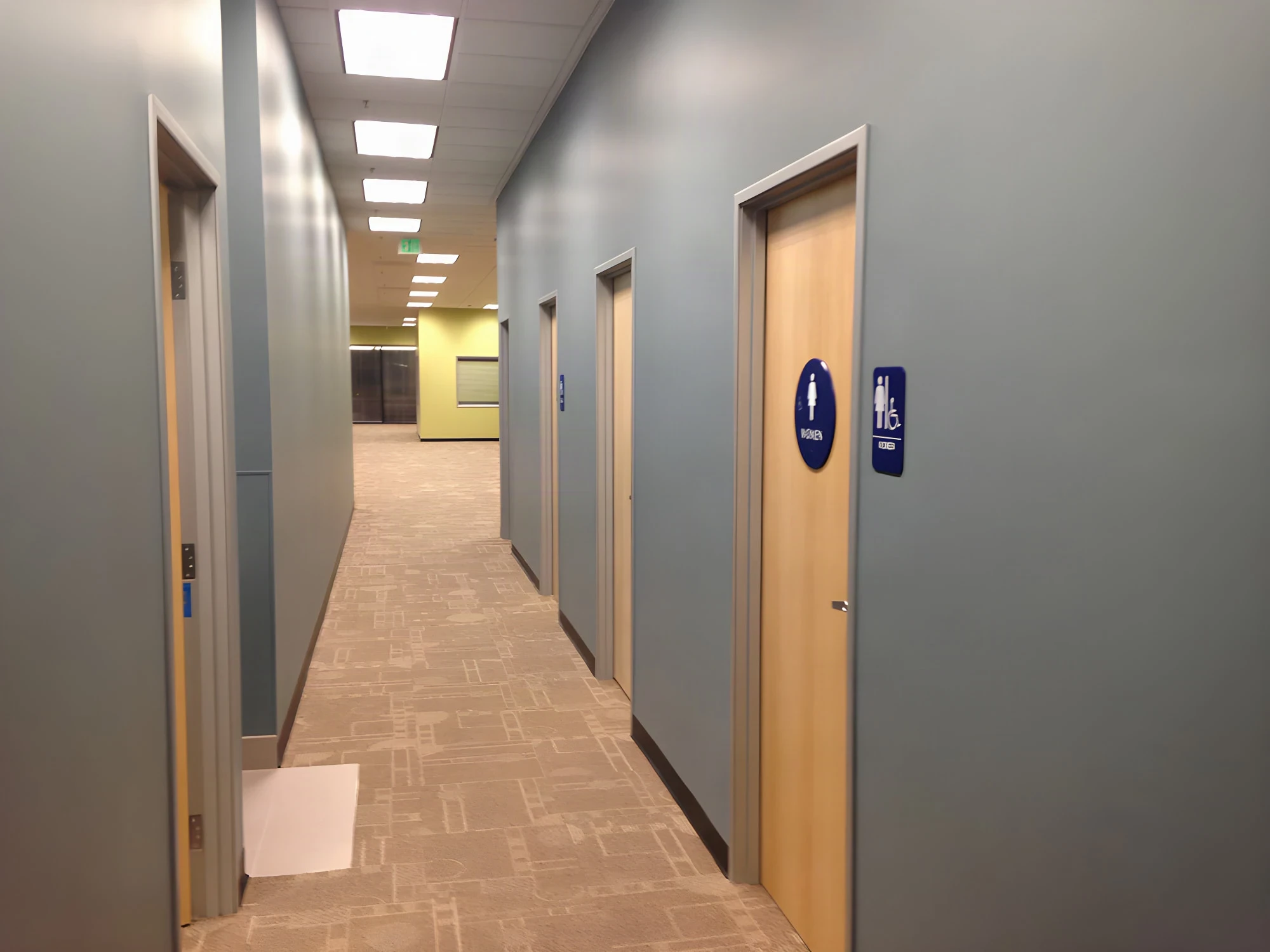 Carpeted corridor with wood restroom doors and blue signage at an Army career center
