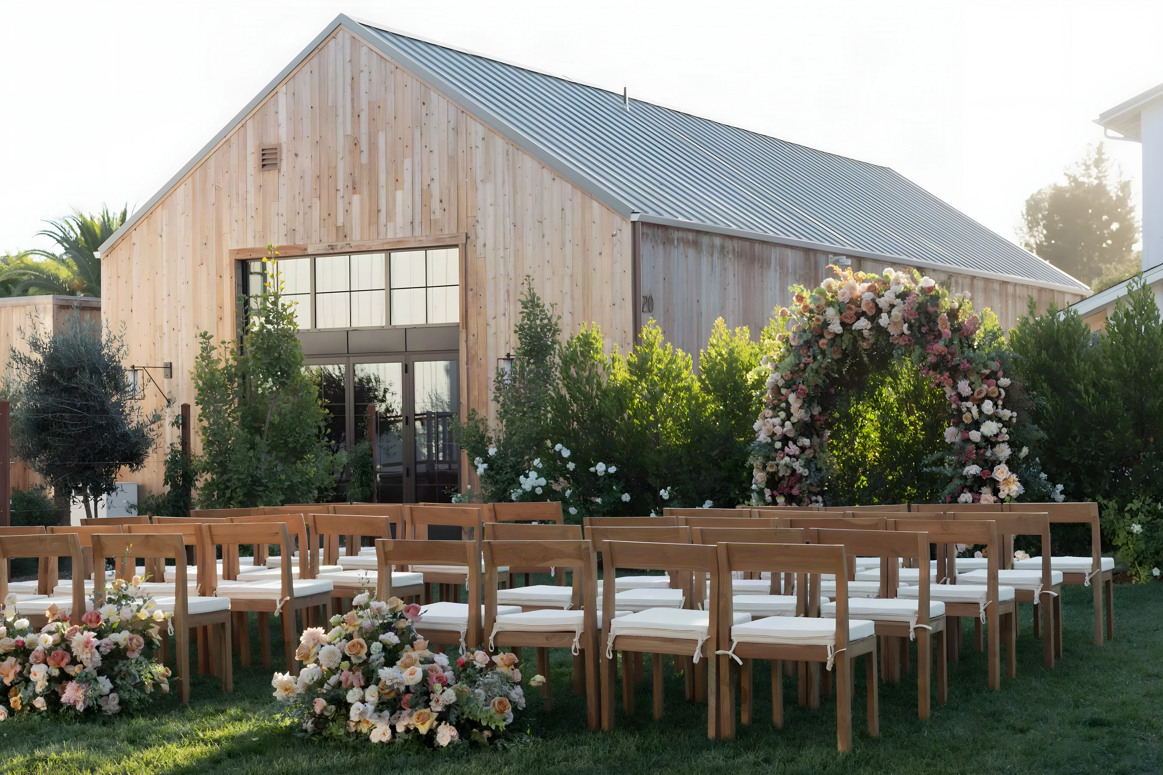 Timber-clad event barn at Mattei’s Inn with a floral arch and ceremony chairs on the lawn