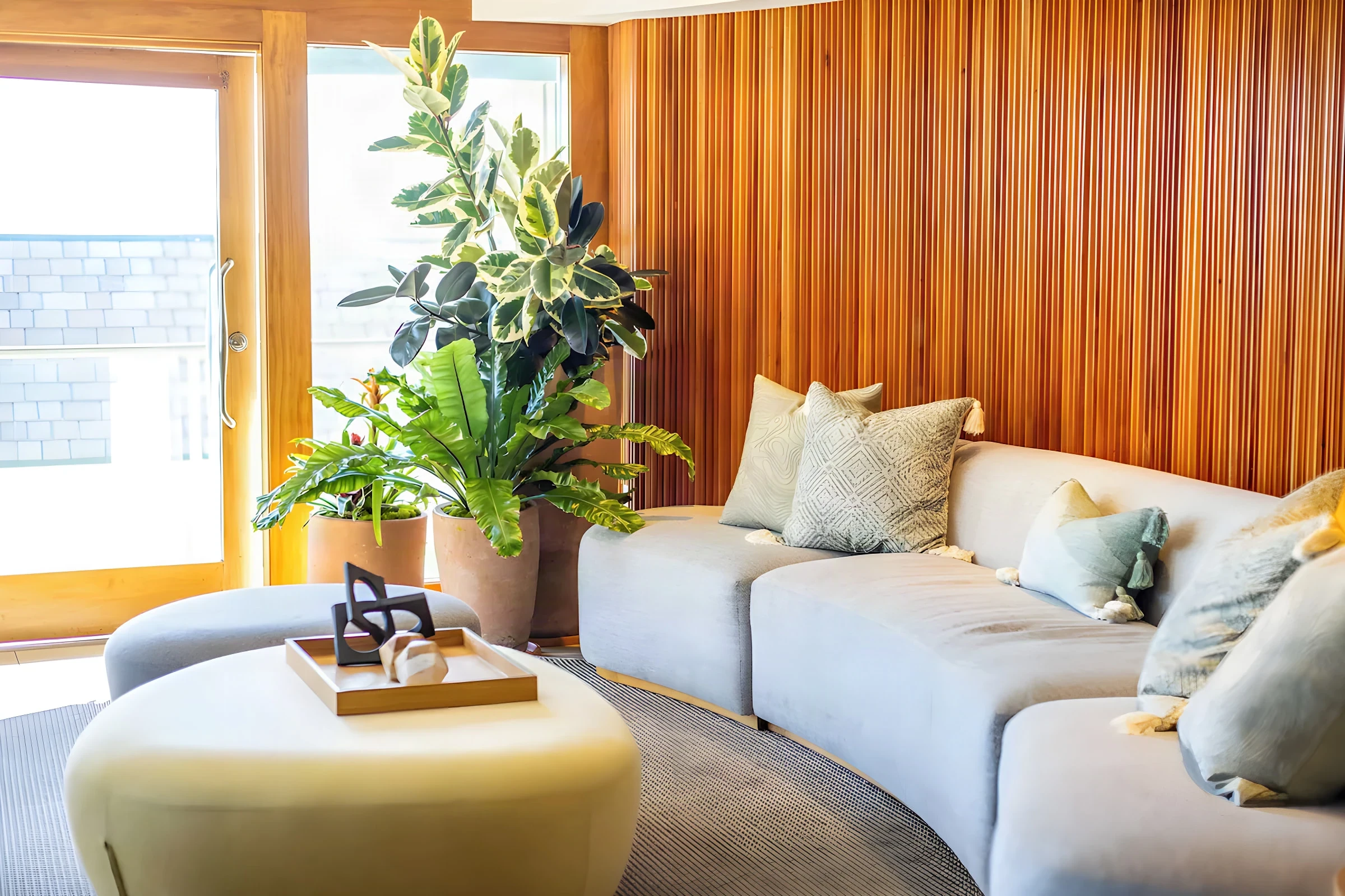 Beach Terrace Inn lounge with a curved grey sofa, potted plants and a slatted timber wall