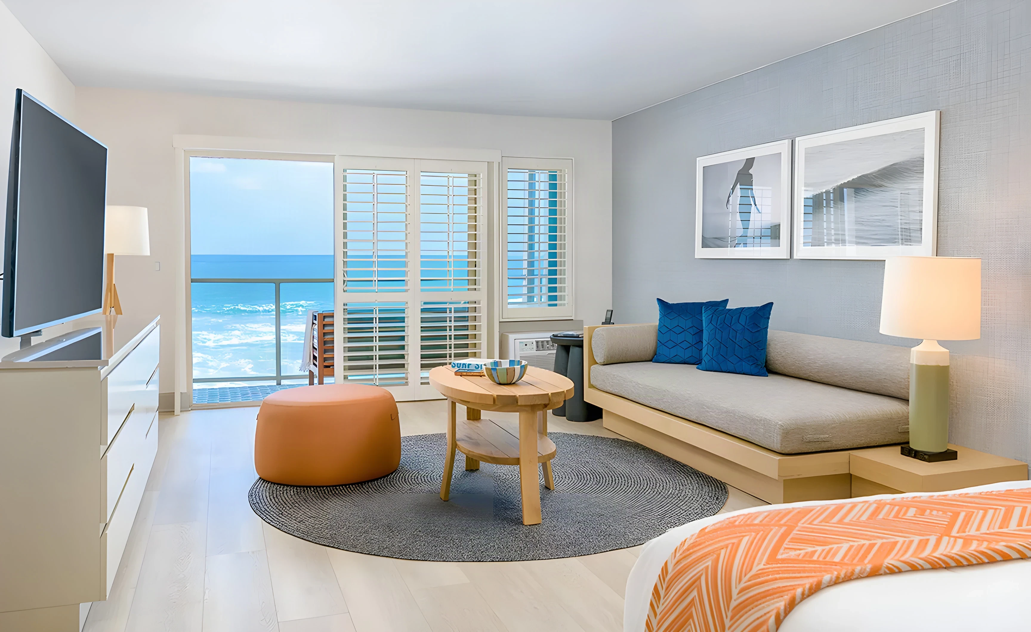 Beach Terrace Inn guest room with an orange ottoman, sofa and a balcony over the ocean