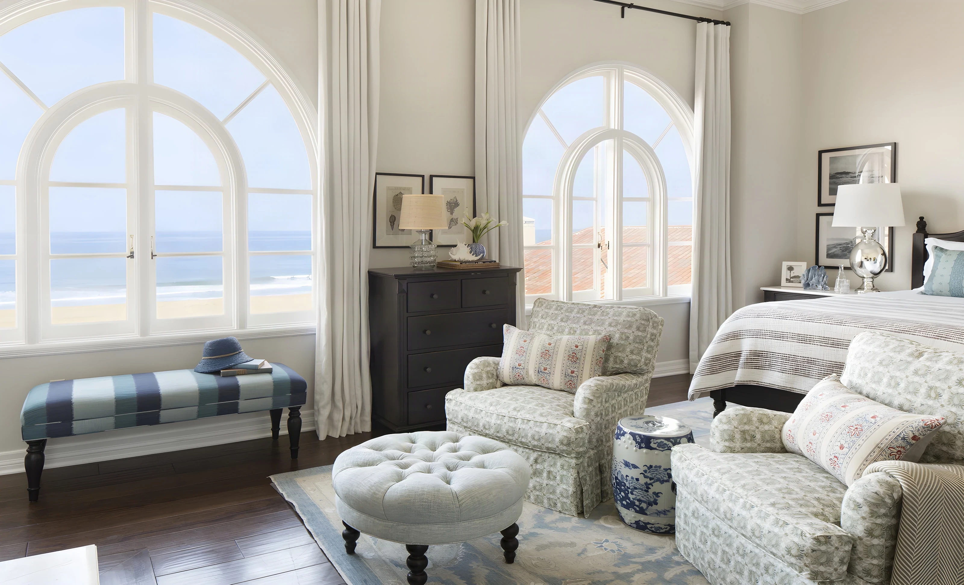 Guest bedroom with arched ocean-view windows and a tufted ottoman at Casa del Mar