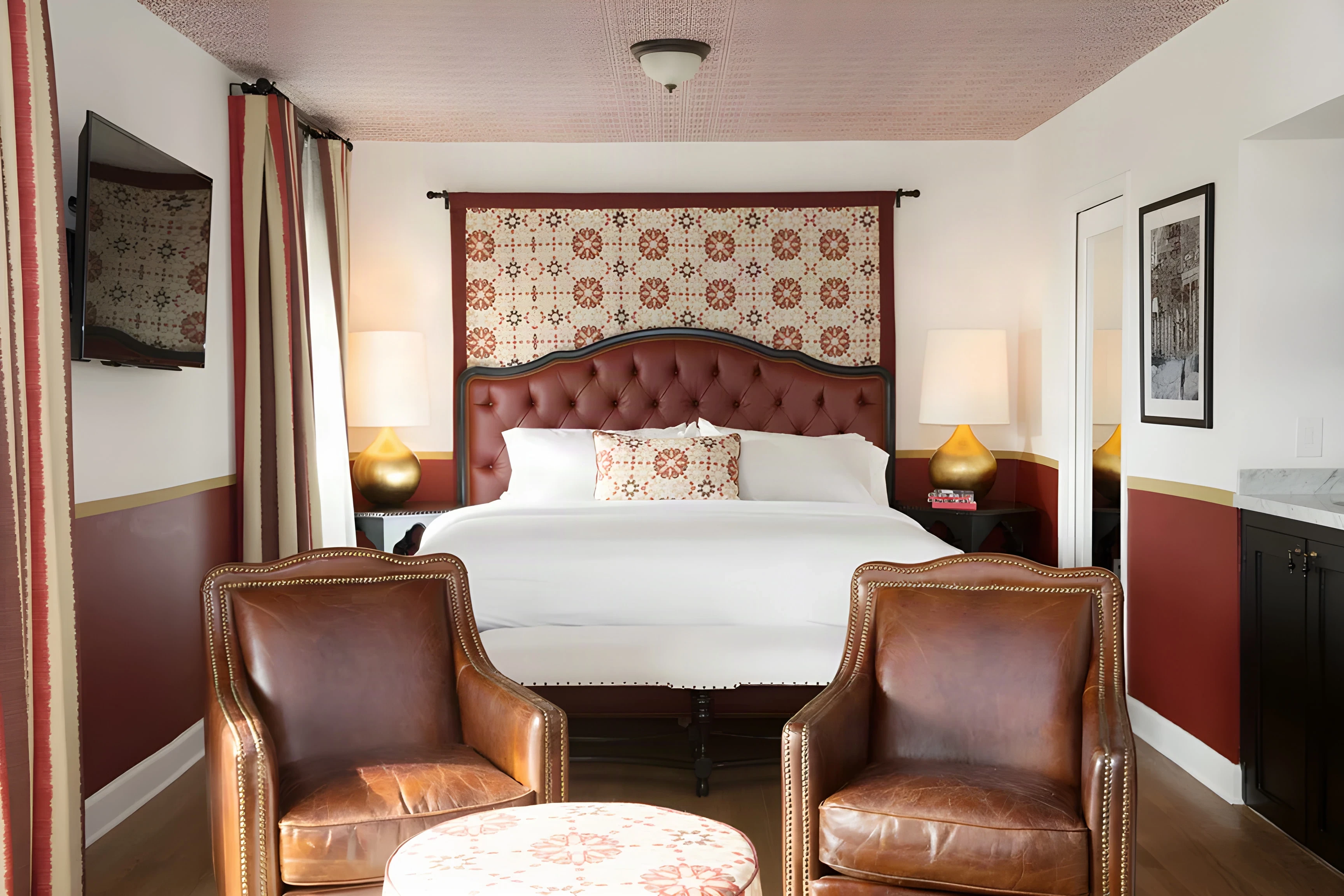 Casa Laguna king room with a tufted headboard, patterned ceiling and leather armchairs