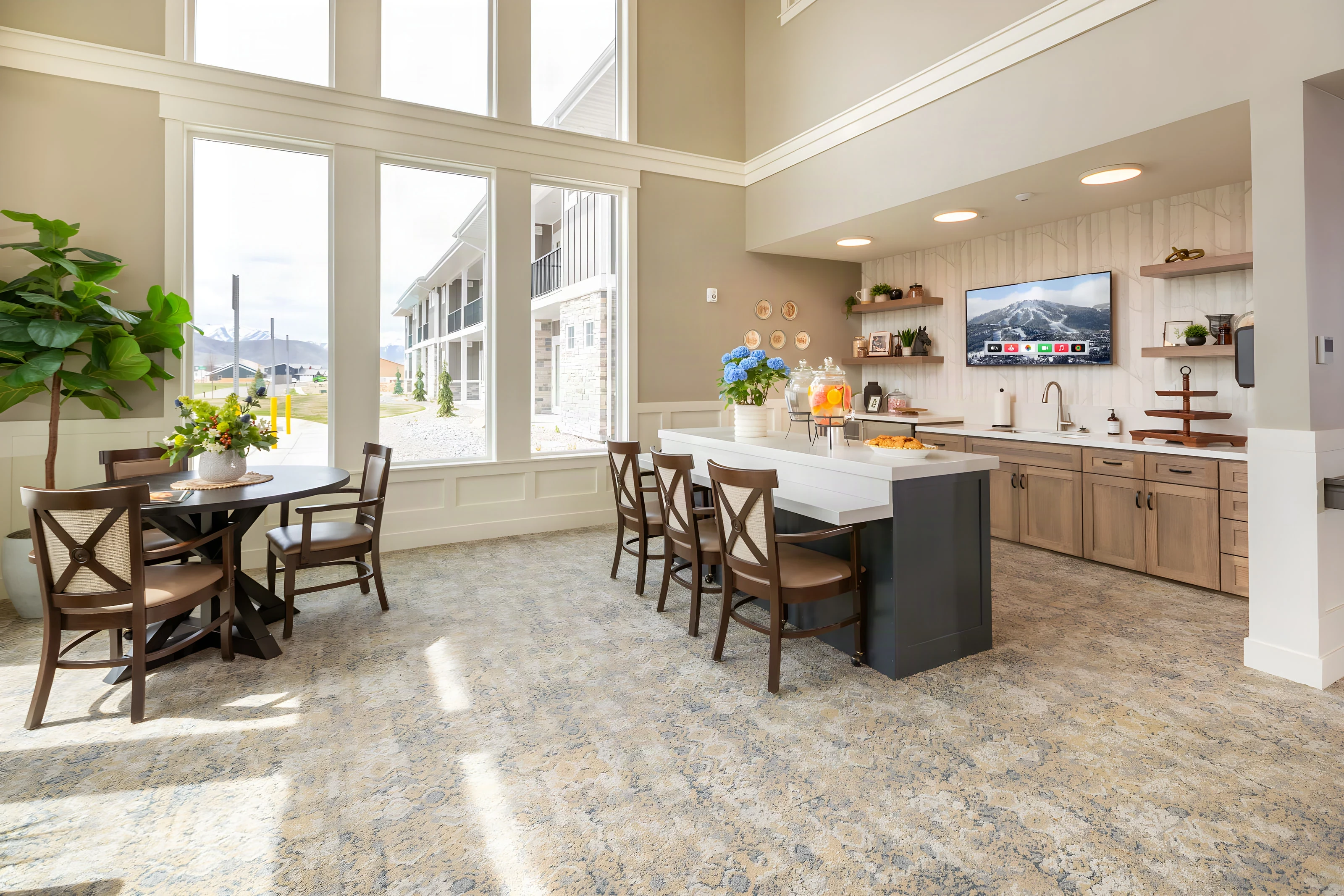 Bright community kitchen with an island and dining tables at The Covington