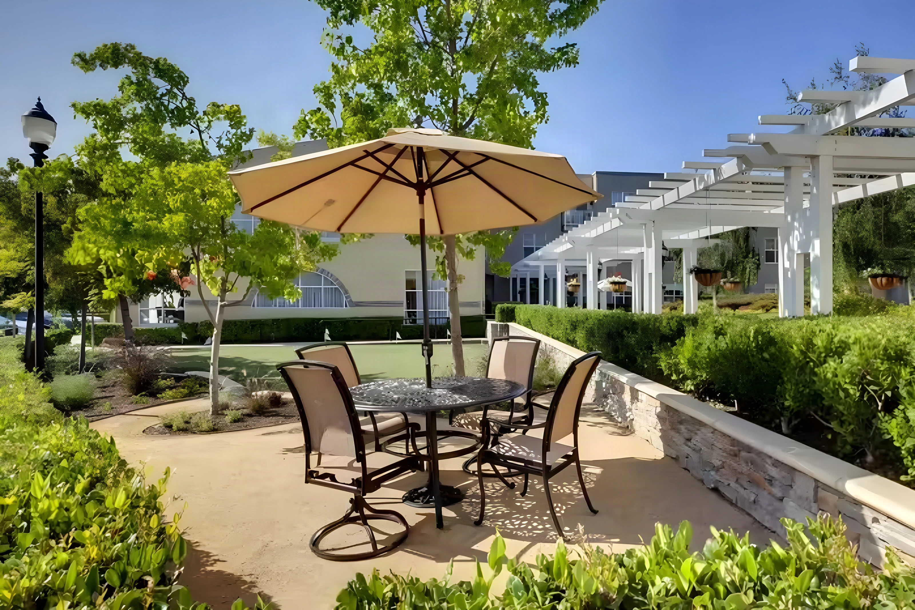 Umbrella patio beside a putting green and pergola at The Covington