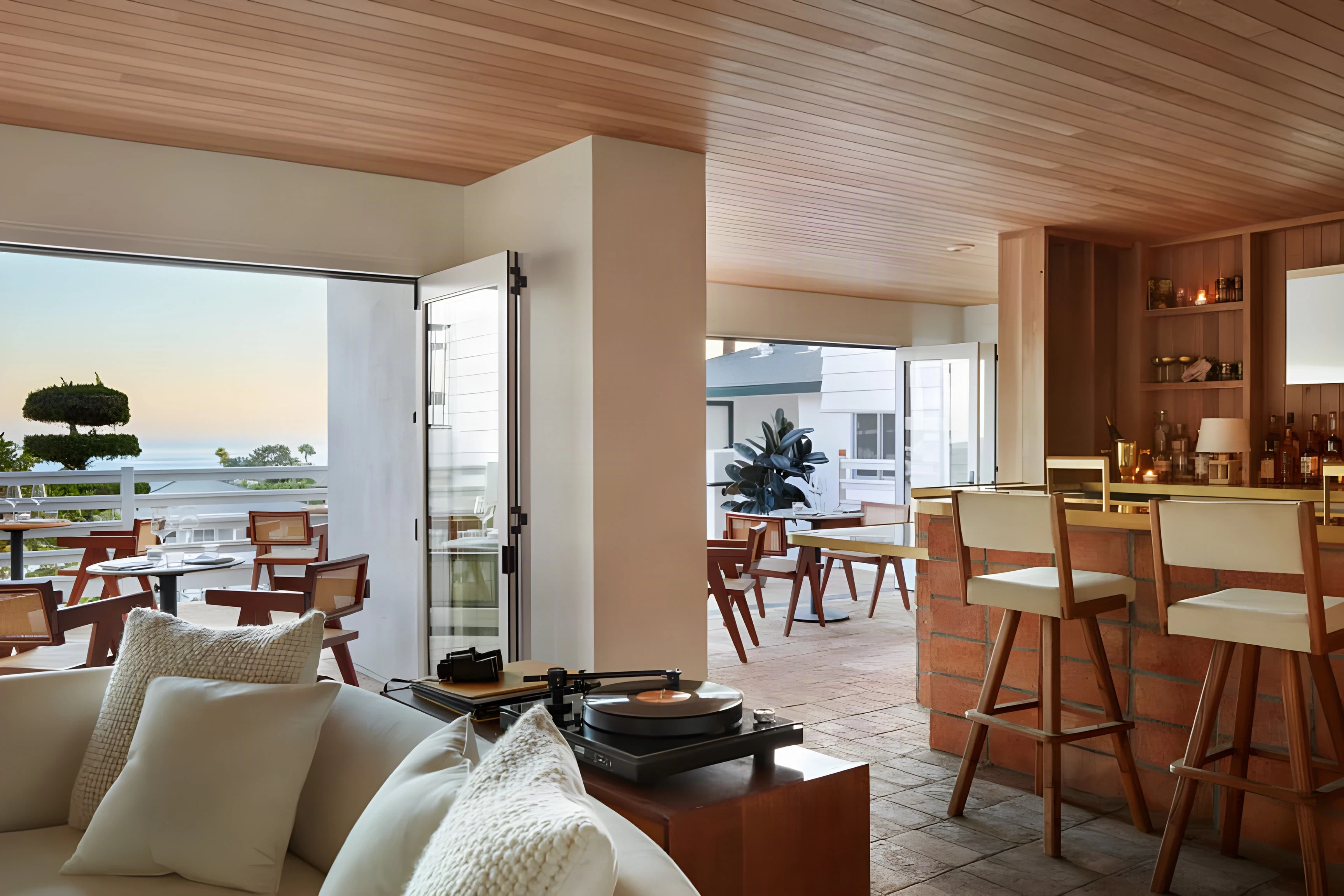 Laguna Beach lounge with a turntable, timber bar and doors open to a sunset terrace