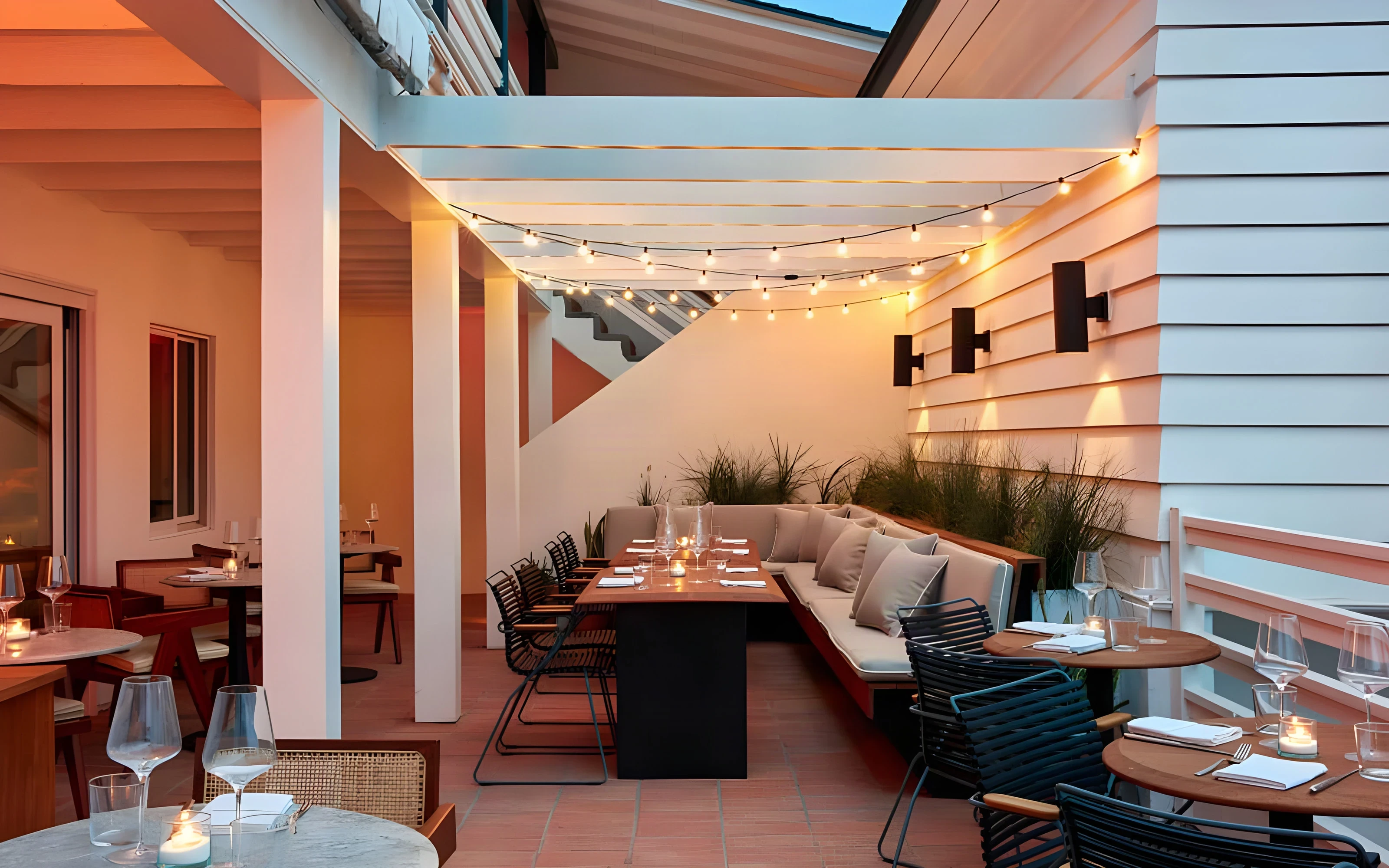 Evening patio with string lights, cushioned banquettes and dining tables at the Laguna Beach hotel
