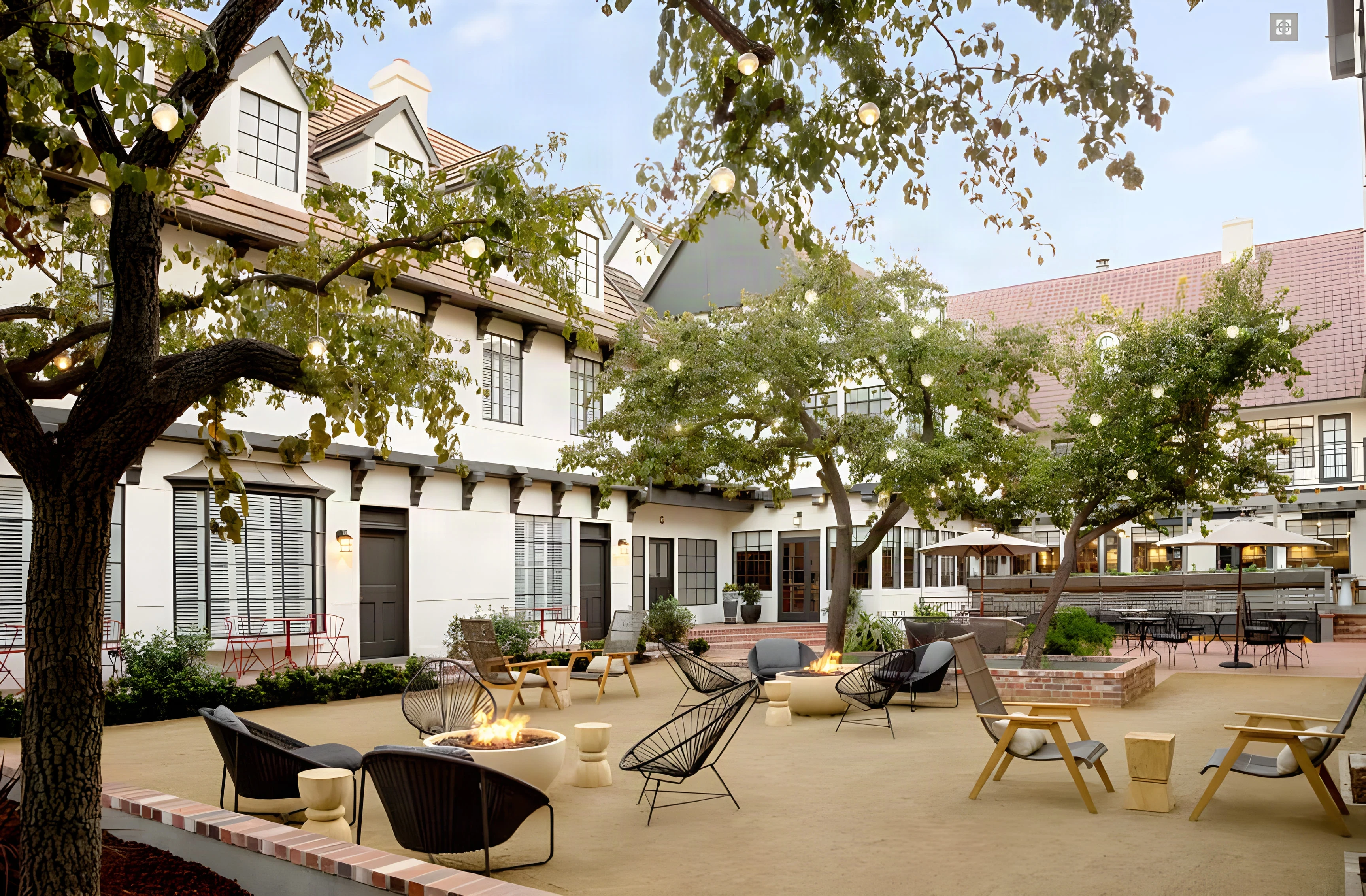 The Landsby courtyard with fire pits, sling chairs and trees before the half-timbered wings