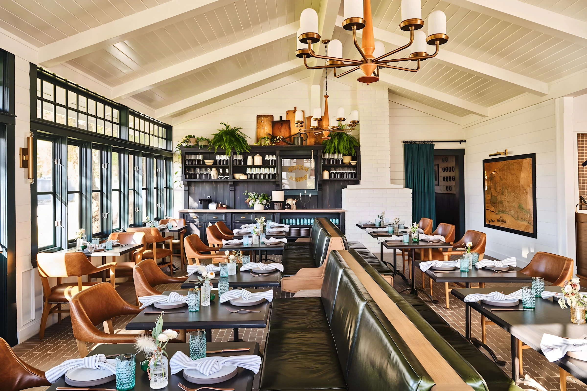 Mattei’s Tavern dining room with green leather banquettes, white beamed ceiling and a brass chandelier
