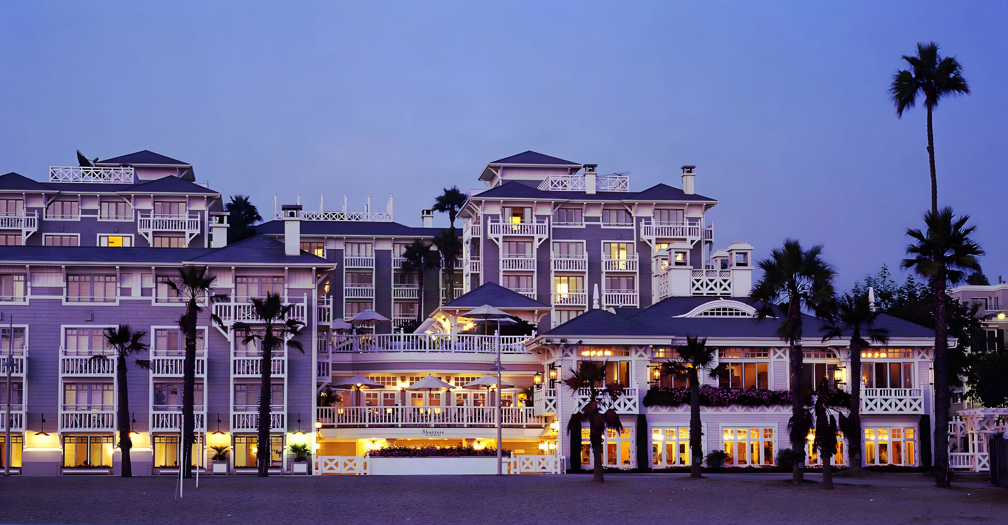 Shutters on the Beach hotel in Santa Monica at dusk with lit balconies, palm trees and a glowing terrace