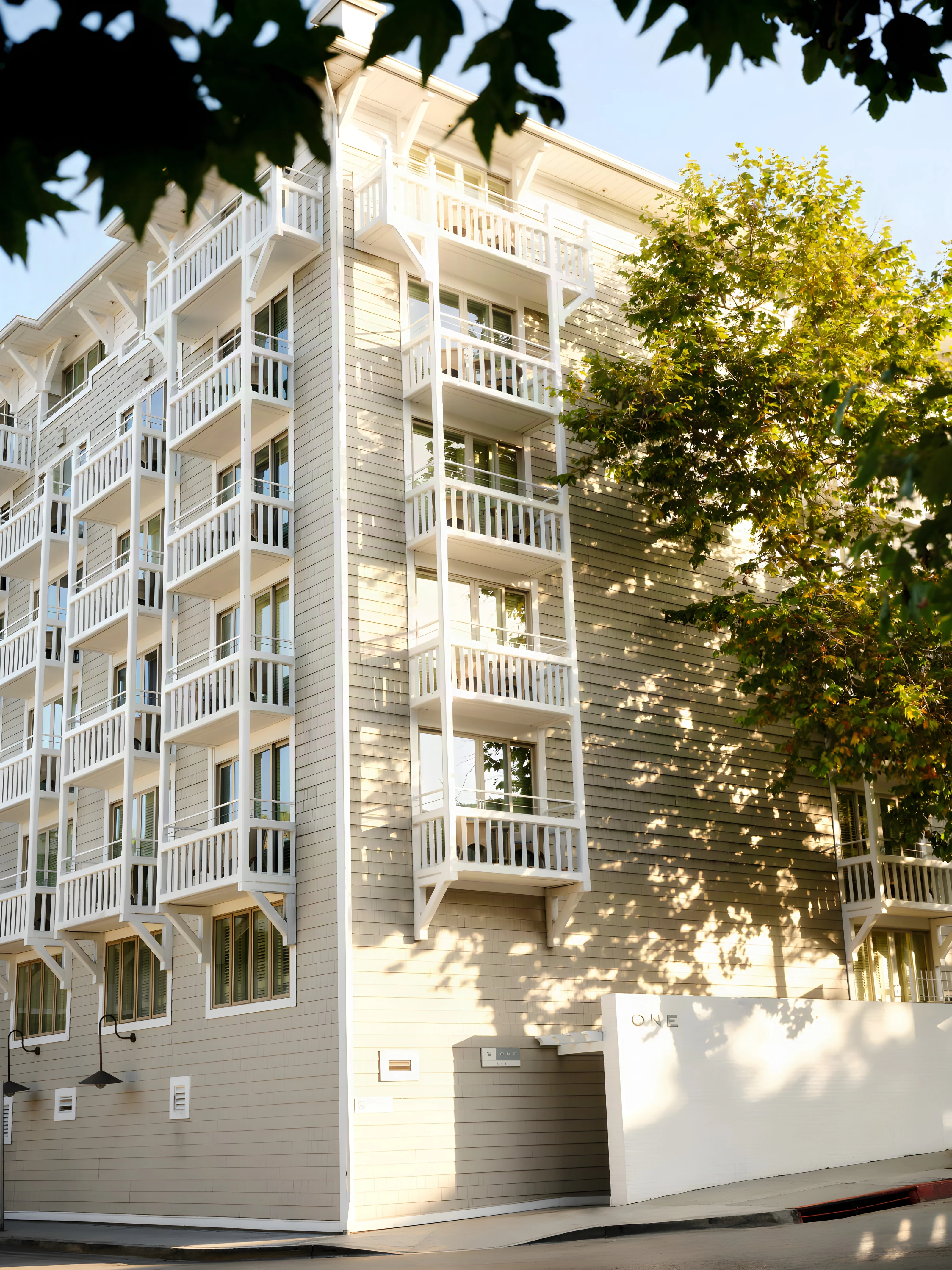 Shingled side elevation and balconies of Shutters on the Beach in dappled light