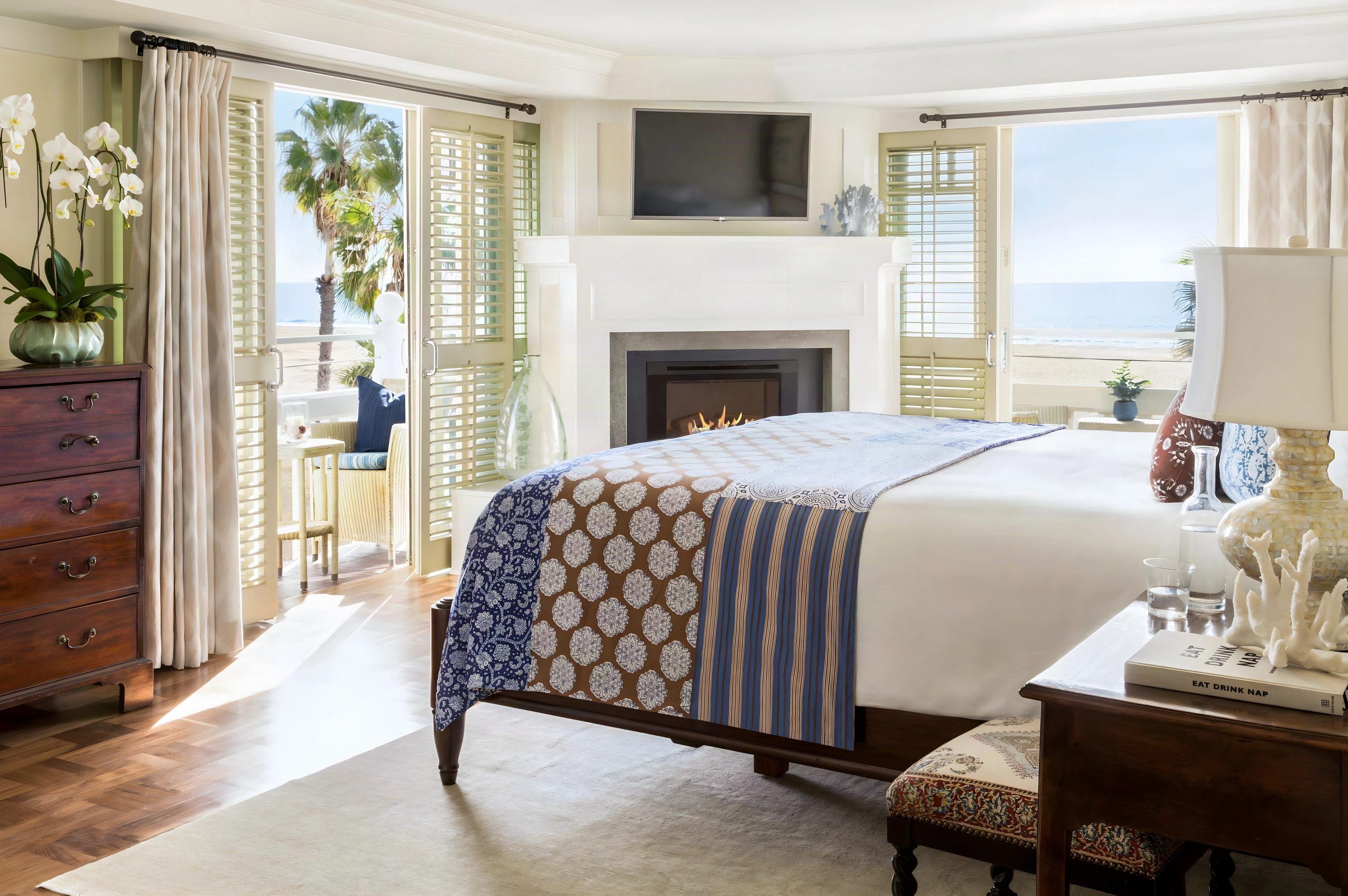 Shutters on the Beach suite bedroom with a patterned throw and open shutters to the ocean