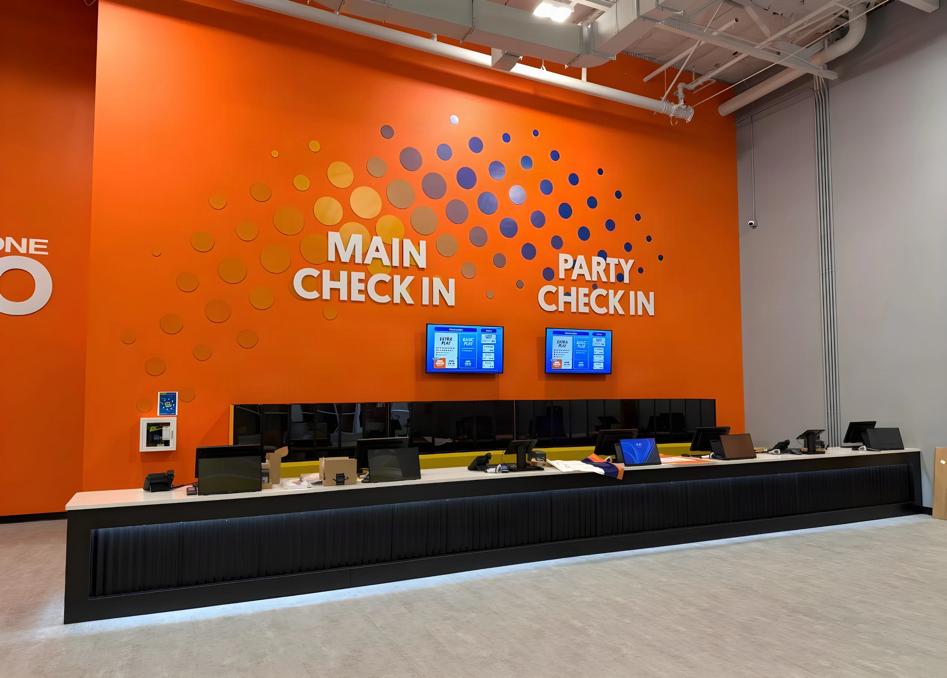 Orange main and party check-in wall with a long service counter at Sky Zone Frisco
