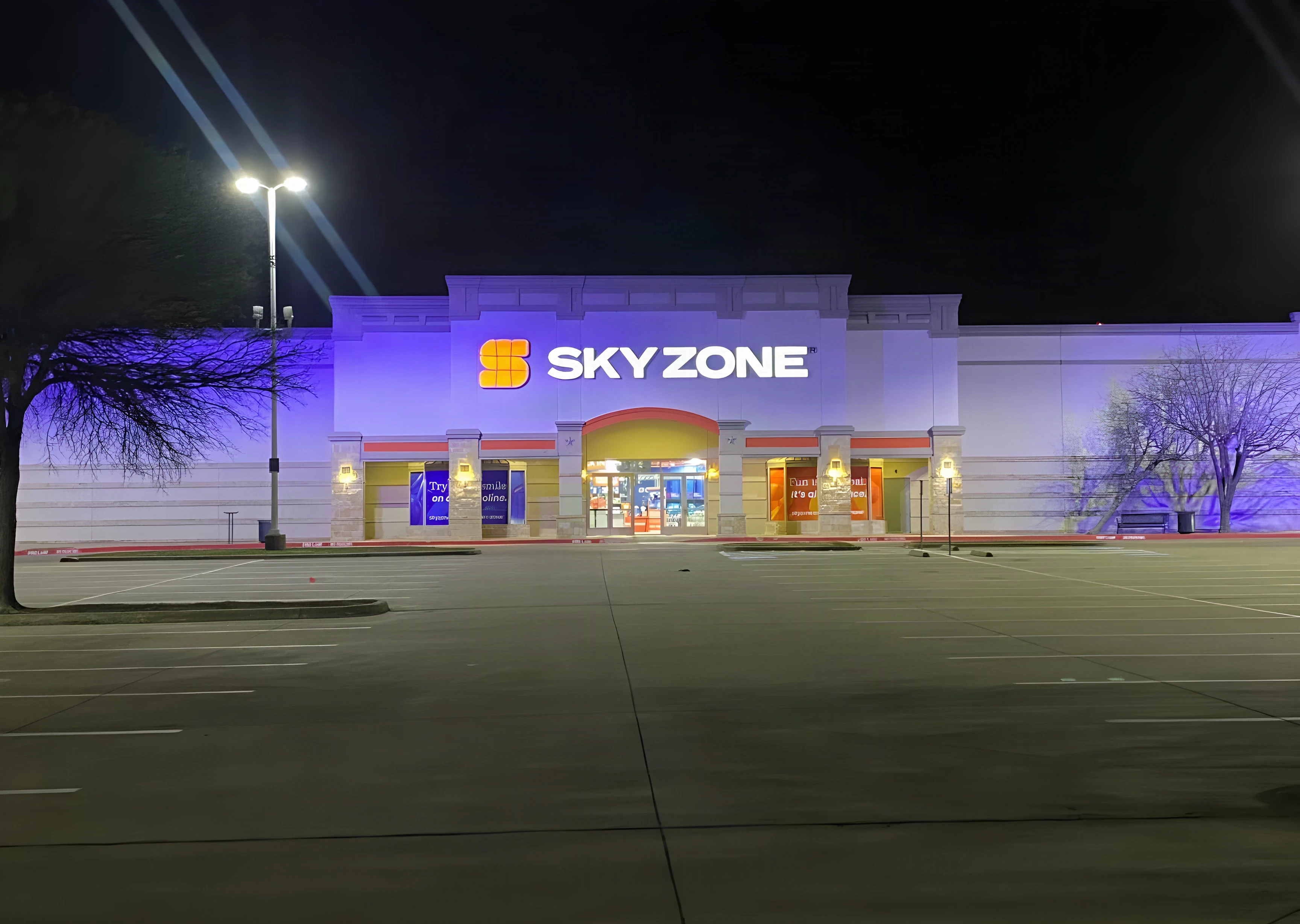 Sky Zone Frisco storefront lit at night across the empty parking lot