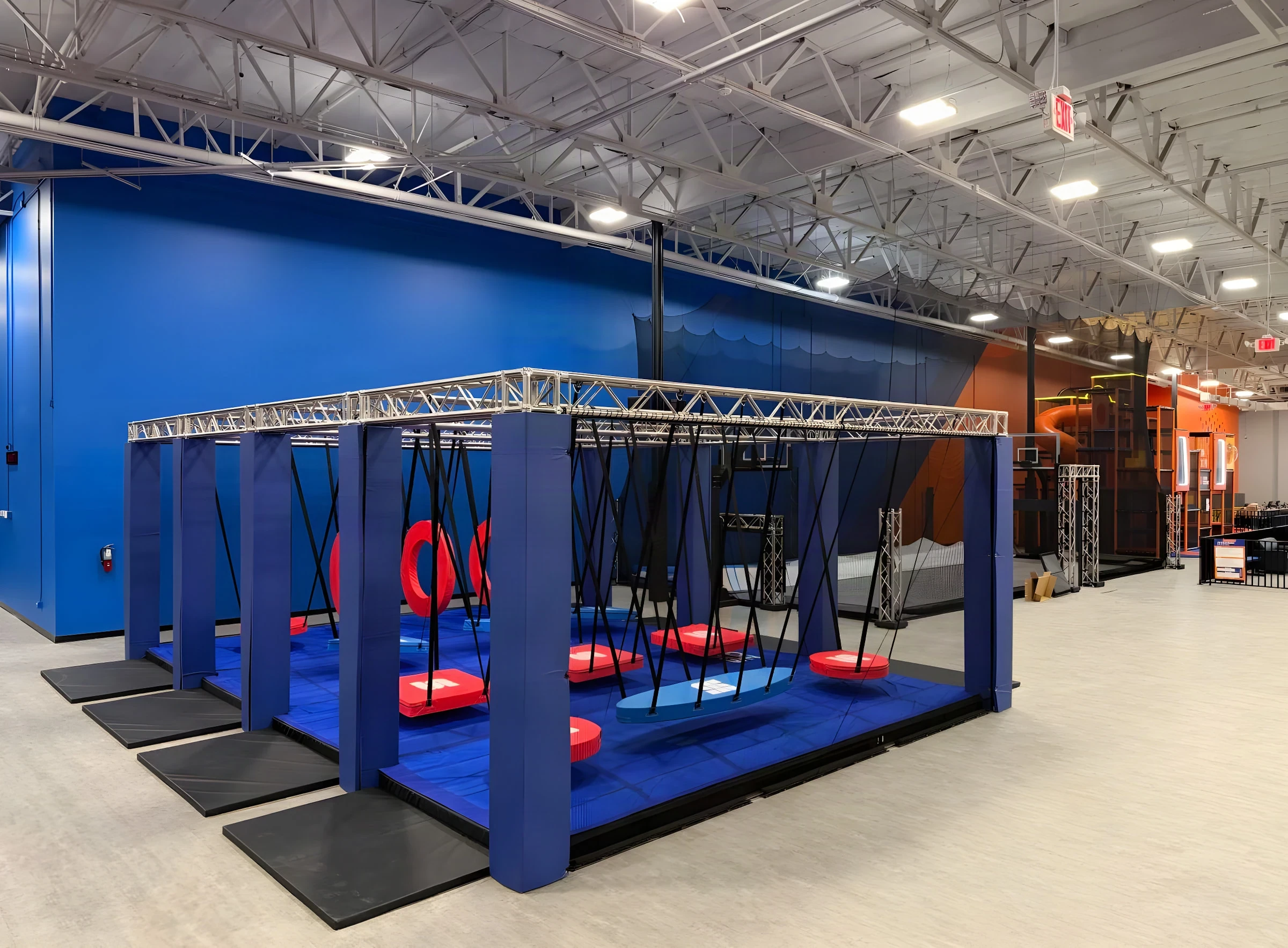 Blue ninja course rig with red swinging pads on the Sky Zone Frisco floor