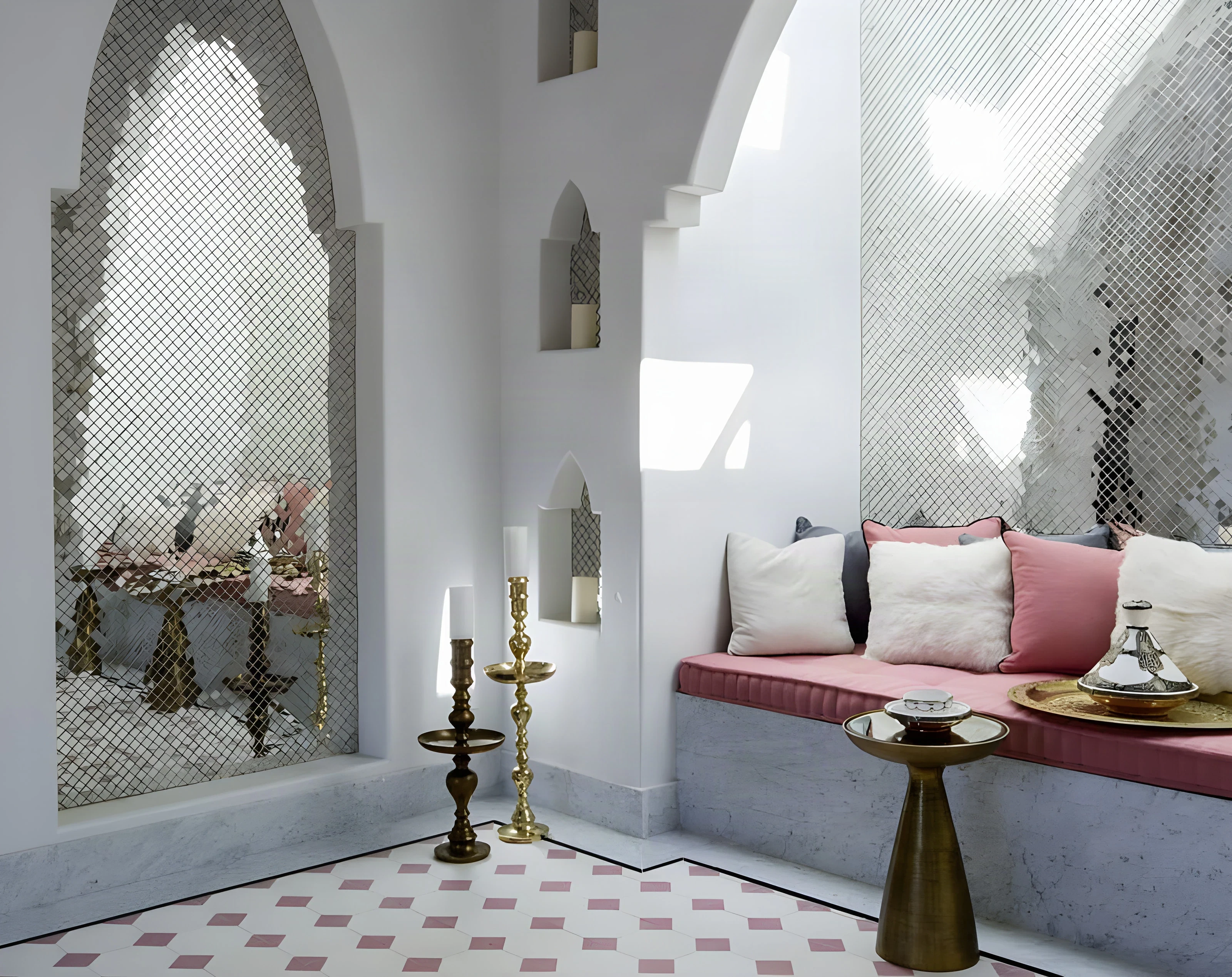 Brass side tables and pink cushions beneath a mirrored arch in the Indian Wells spa