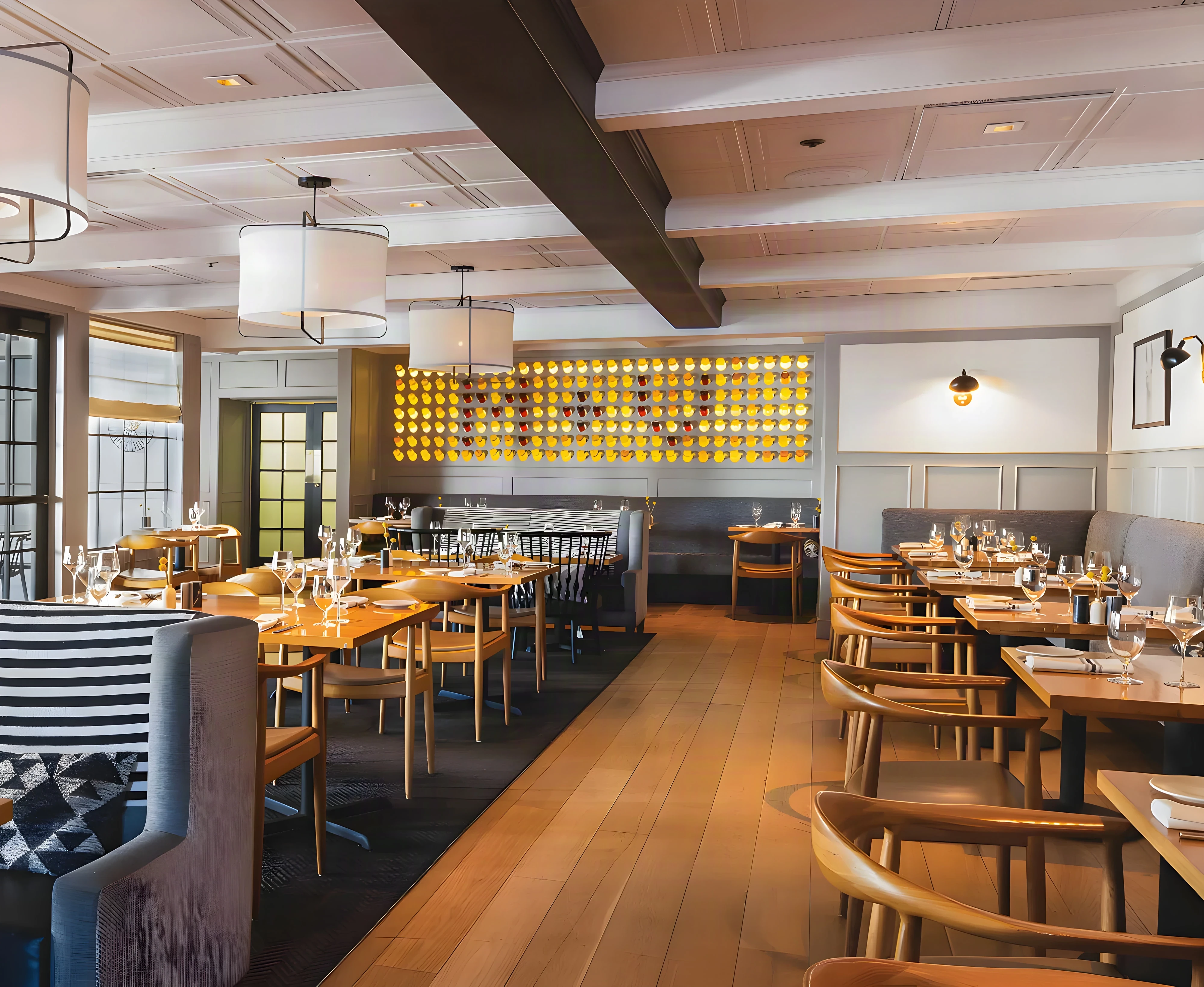 Mad & Vin dining room with grey banquettes, oak tables and a glowing wine bottle wall in Solvang